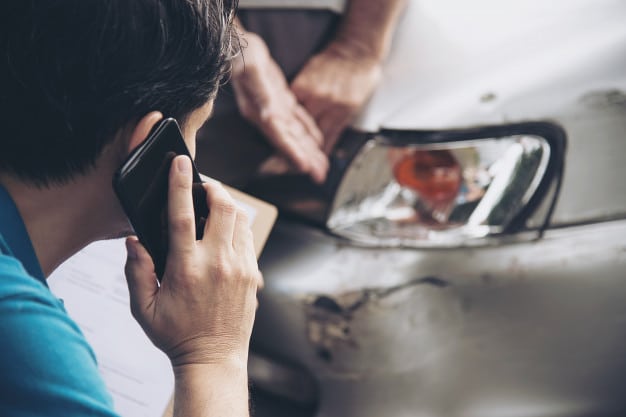 homme au téléphone devant accident de voiture